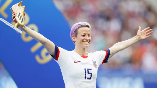 Megan Rapinoe holds her arms out in celebrations while holding the Golden Boot trophy for top goalscorer at the 2019 Women's World Cup.